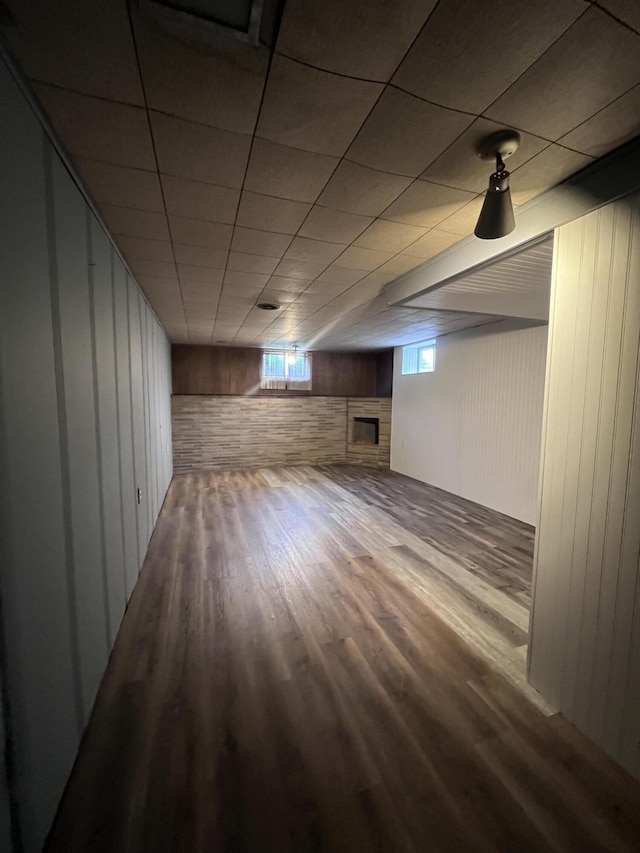 below grade area featuring wood finished floors, wood walls, and a fireplace