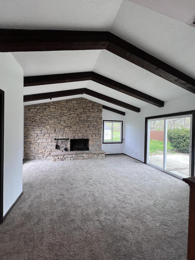 unfurnished living room with carpet floors, a textured ceiling, and a stone fireplace