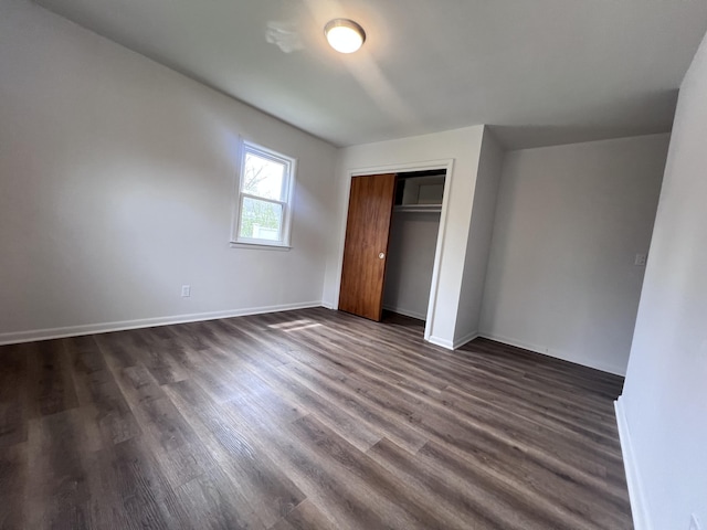 unfurnished bedroom with dark wood finished floors, a closet, and baseboards