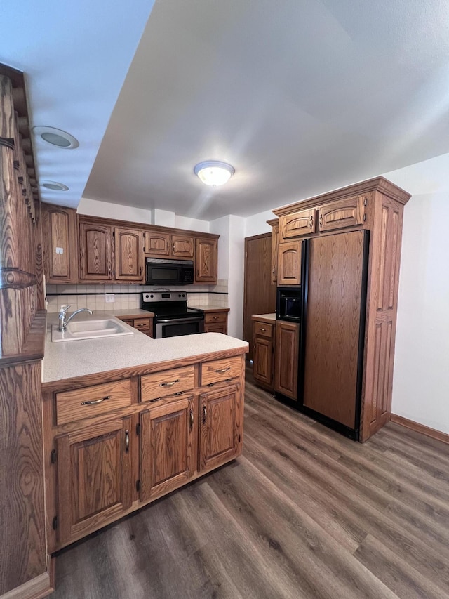 kitchen with stainless steel range with electric stovetop, black microwave, a sink, refrigerator, and dark wood-style flooring