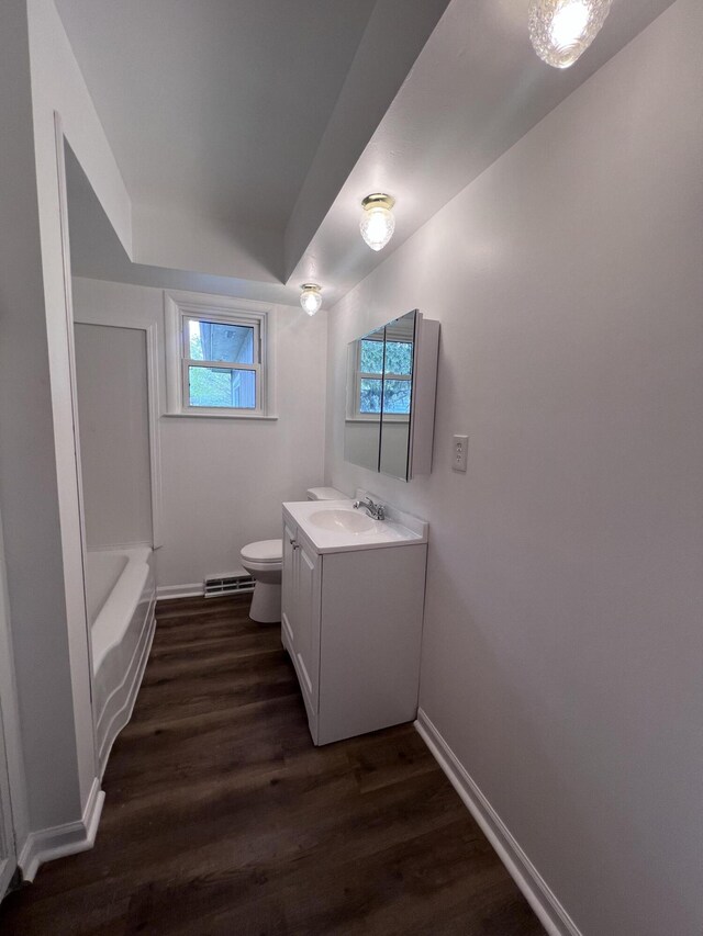bathroom featuring toilet, wood finished floors, vanity, baseboards, and baseboard heating