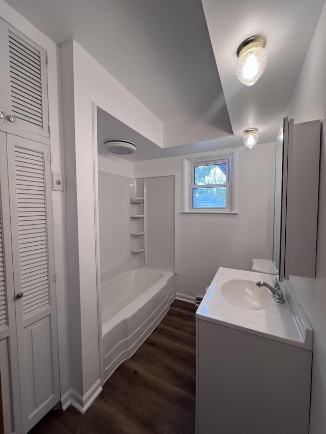 bathroom with wood finished floors, vanity, baseboards, and  shower combination