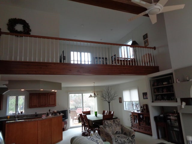 living room with a ceiling fan, a towering ceiling, light carpet, and plenty of natural light
