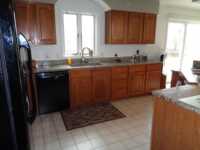 kitchen with black appliances, a sink, brown cabinets, and light stone counters