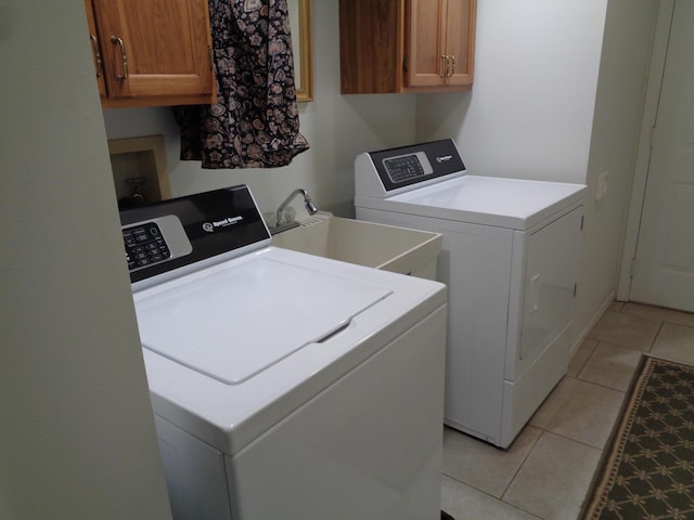 laundry room with cabinet space, washing machine and dryer, and light tile patterned floors