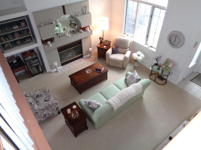 carpeted living area featuring a tile fireplace and baseboards