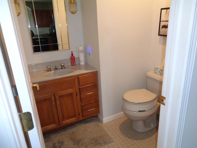 bathroom featuring toilet, vanity, and baseboards