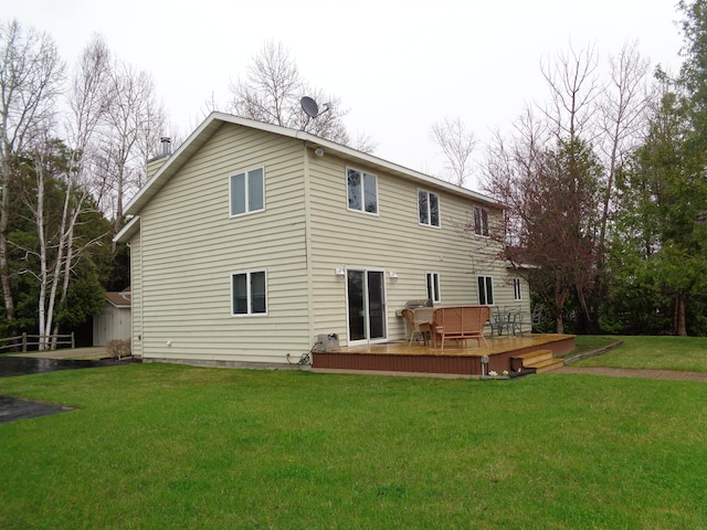 back of house featuring a deck, a lawn, a chimney, and a shed