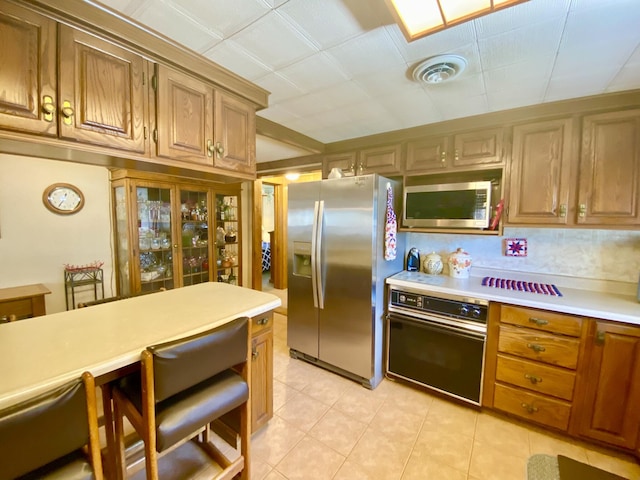 10328 Toohy Trl, Harrison, MI 48625 - kitchen featuring appliances with stainless steel finishes, light countertops, light tile patterned flooring, and brown cabinets