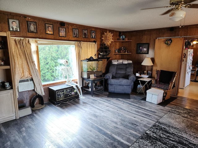 sitting room with wood walls, ceiling fan, wood finished floors, a textured ceiling, and cooling unit