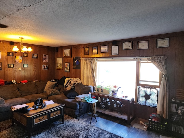 living room with a textured ceiling, a chandelier, wooden walls, and wood finished floors