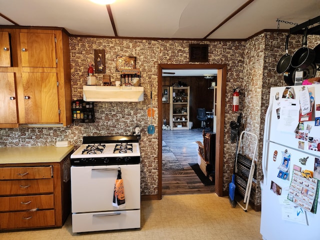 kitchen with white appliances, ventilation hood, light floors, brown cabinetry, and light countertops