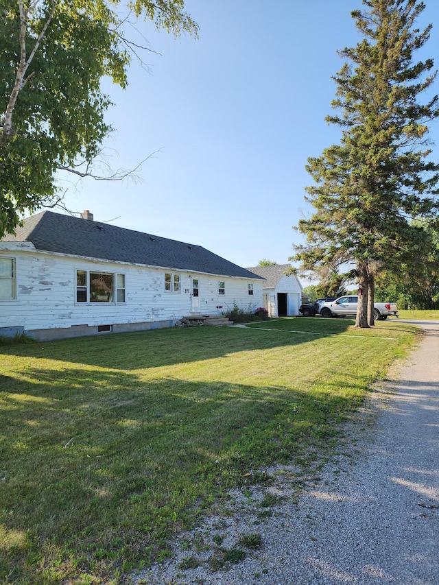 view of front facade featuring a front lawn, a chimney, gravel driveway, a garage, and a storage shed