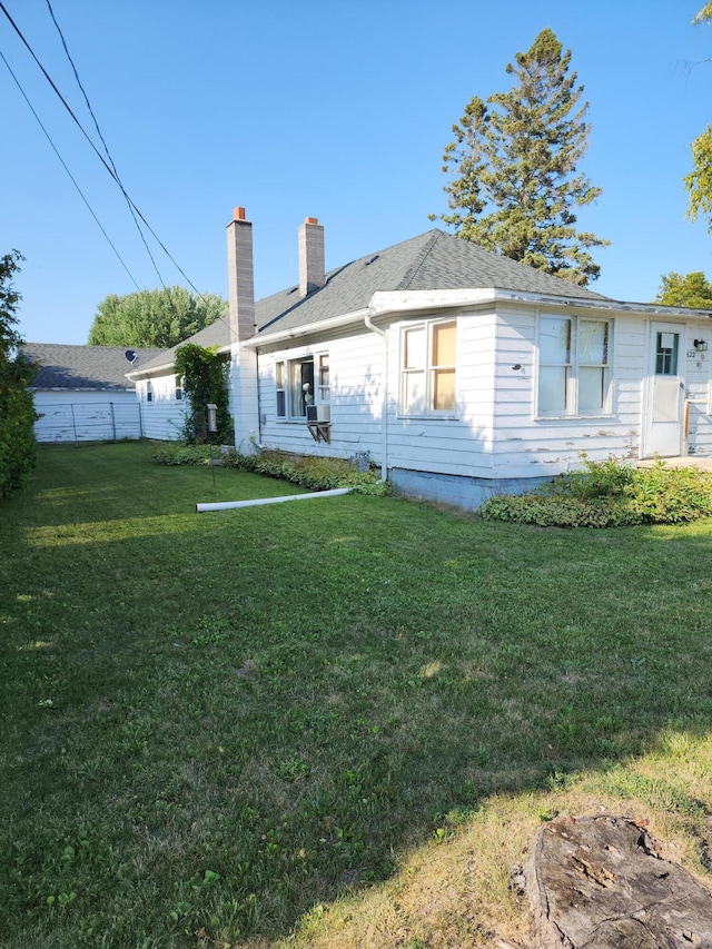 back of house featuring a chimney and roof with shingles