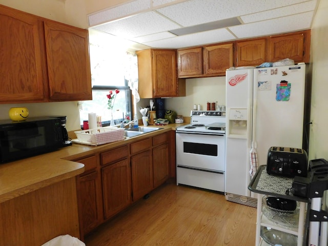 8727 S Oak Rd, Grayling, MI 49738 - kitchen featuring white appliances, brown cabinetry, light wood-style floors, light countertops, and a sink