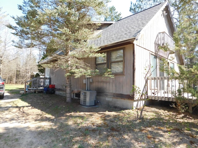8727 S Oak Rd, Grayling, MI 49738 - view of side of property featuring roof with shingles, central AC, and a deck