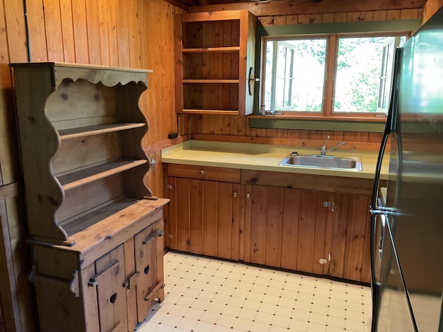 8842 Jackson Hole Trl, Grayling, MI 49738 - kitchen with freestanding refrigerator, a sink, wood walls, light countertops, and brown cabinetry