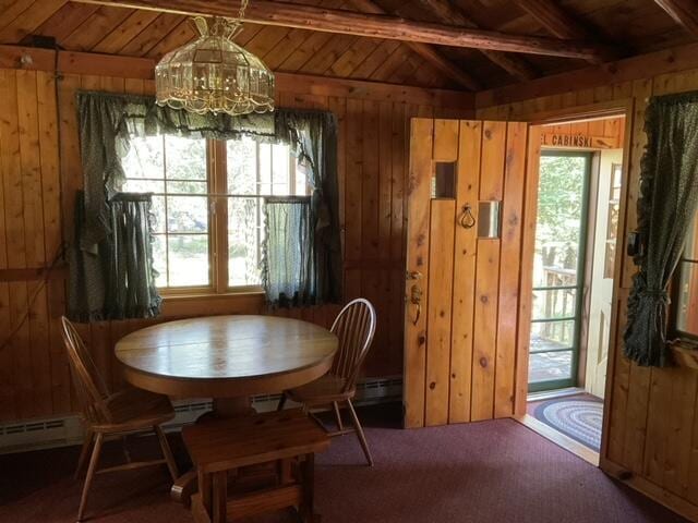 8842 Jackson Hole Trl, Grayling, MI 49738 - carpeted dining room with a baseboard heating unit, wooden walls, a chandelier, wood ceiling, and a baseboard radiator