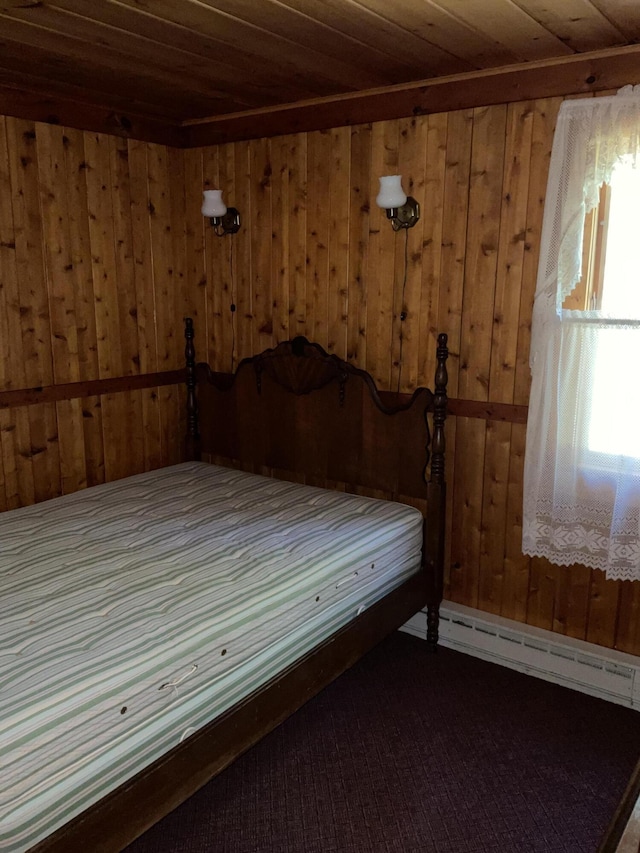 8842 Jackson Hole Trl, Grayling, MI 49738 - bedroom with wood walls, baseboard heating, wooden ceiling, and dark colored carpet