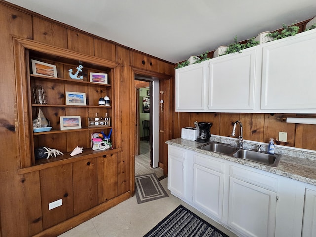 204 Broadway Rd, Houghton Lake, MI 48629 - kitchen featuring a sink, wood walls, white cabinetry, and light stone countertops