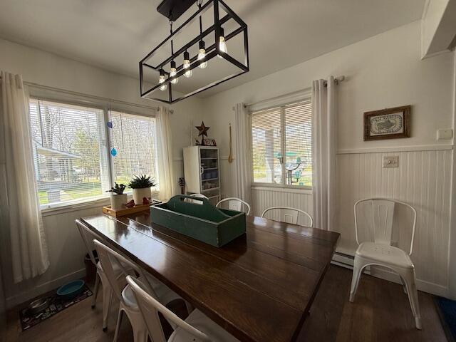 dining space featuring wood finished floors, wainscoting, a chandelier, and baseboard heating