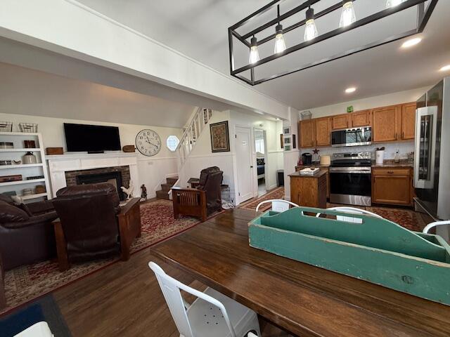 dining room with stairs, a brick fireplace, and dark wood-style floors