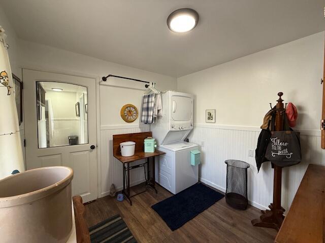 washroom featuring stacked washer / dryer, wood finished floors, and wainscoting