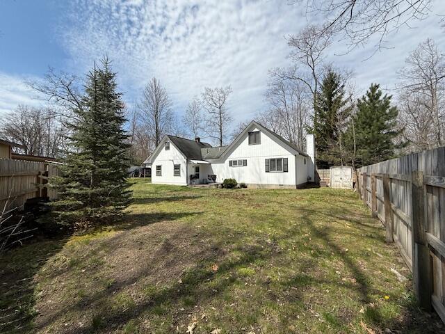 back of house featuring a shed, an outdoor structure, and a chimney
