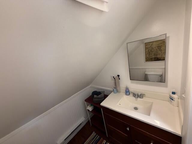 bathroom with lofted ceiling, vanity, toilet, and a wainscoted wall