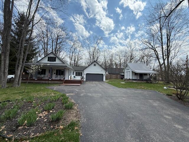view of front facade featuring a porch, asphalt driveway, a garage, and a front yard