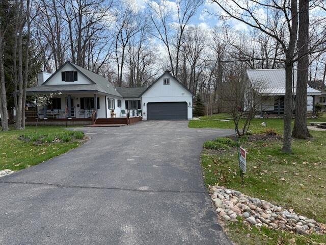 view of front of property featuring a porch, driveway, an attached garage, and a front yard
