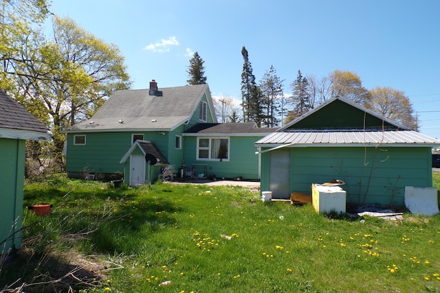 1220 Court St, Cheboygan, MI 49721 - rear view of property featuring a lawn, a chimney, and an outbuilding
