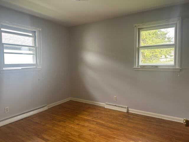 spare room featuring baseboard heating, wood finished floors, and baseboards