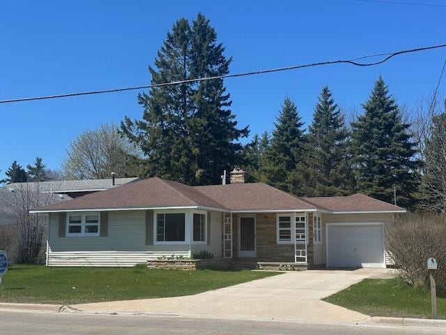 ranch-style home featuring an attached garage, concrete driveway, a front yard, and a chimney