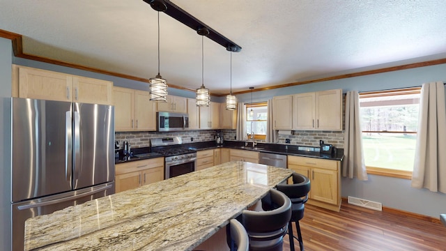 3400 Thornapple Trl, Lewiston, MI 49756 - kitchen with stainless steel appliances, light brown cabinetry, plenty of natural light, ornamental molding, and a textured ceiling