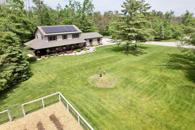 3400 Thornapple Trl, Lewiston, MI 49756 - view of front of home with roof mounted solar panels, roof with shingles, and a wooded view