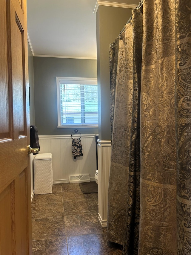 bathroom featuring a wainscoted wall, toilet, and crown molding