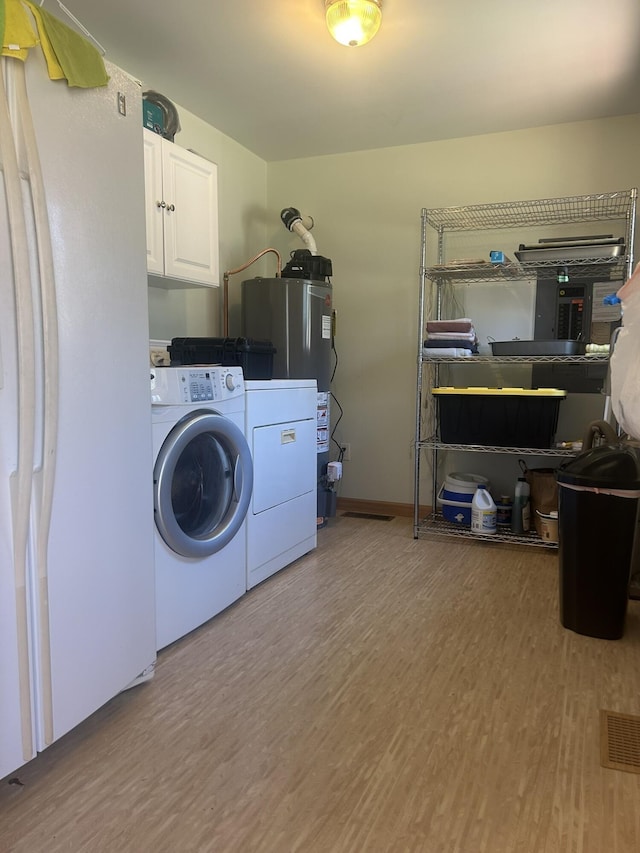 washroom with washing machine and dryer, cabinet space, wood finished floors, and water heater