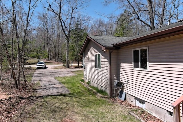 view of home's exterior featuring asphalt driveway, a lawn, and a shingled roof