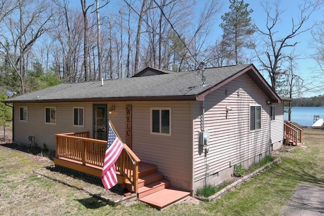 back of property featuring a deck, roof with shingles, and a lawn