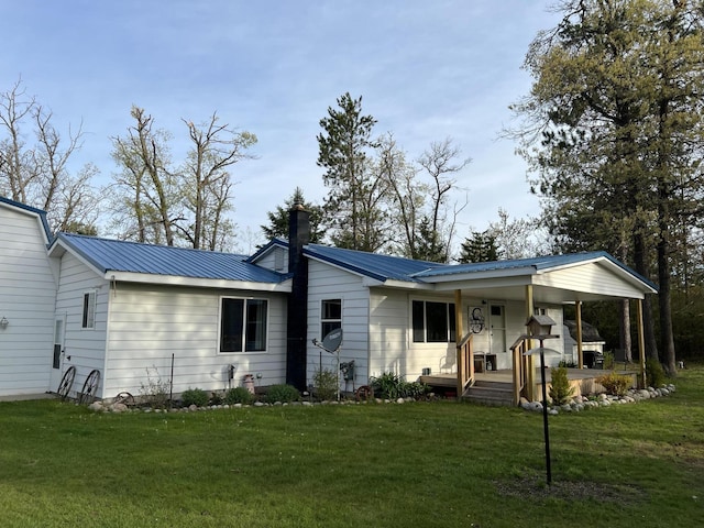 4210 County Road 491, Lewiston, MI 49756 - view of front of house with covered porch, a front lawn, a chimney, and metal roof