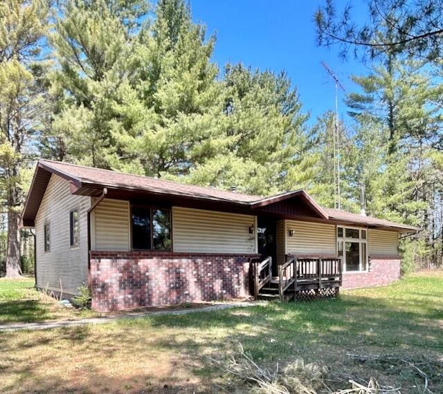 2165 E Cherry Creek Rd, Fairview, MI 48621 - view of front of home featuring brick siding, a front yard, and a deck