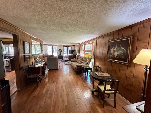 2165 E Cherry Creek Rd, Fairview, MI 48621 - living room with a textured ceiling, hardwood / wood-style floors, and wooden walls