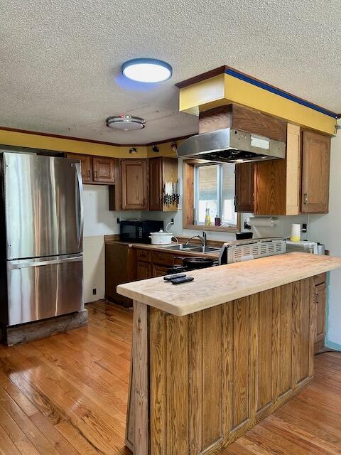 2165 E Cherry Creek Rd, Fairview, MI 48621 - kitchen featuring freestanding refrigerator, a textured ceiling, black microwave, wood counters, and light wood finished floors