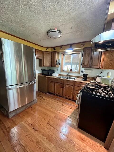 2165 E Cherry Creek Rd, Fairview, MI 48621 - kitchen featuring freestanding refrigerator, gas stove, a textured ceiling, a sink, and brown cabinetry