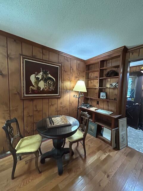 2165 E Cherry Creek Rd, Fairview, MI 48621 - sitting room featuring light wood-style floors, a textured ceiling, and wood walls