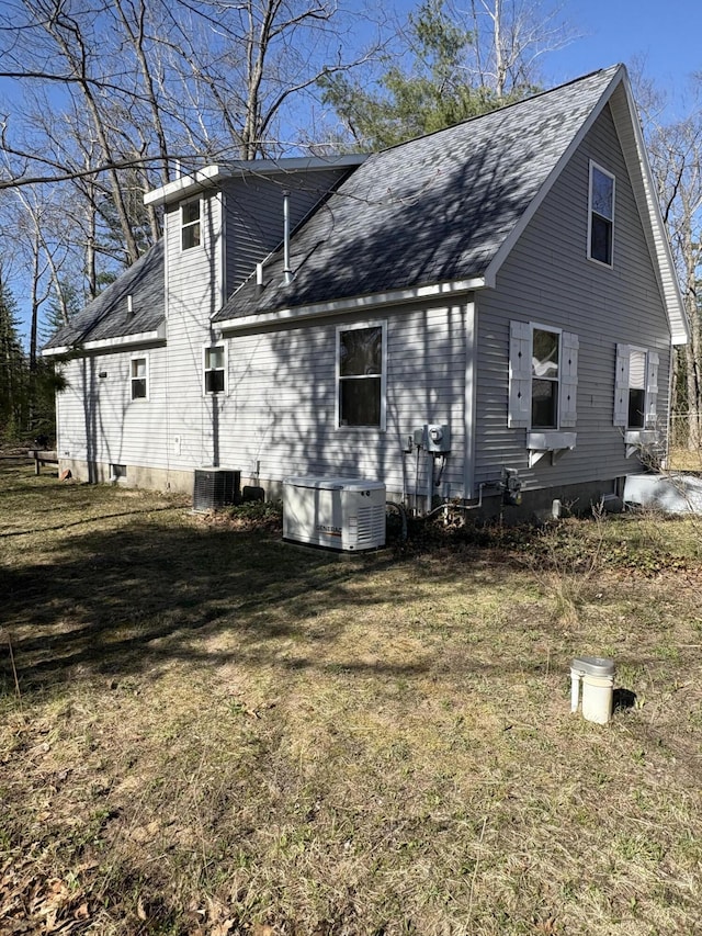 back of property with roof with shingles, central AC, and a lawn