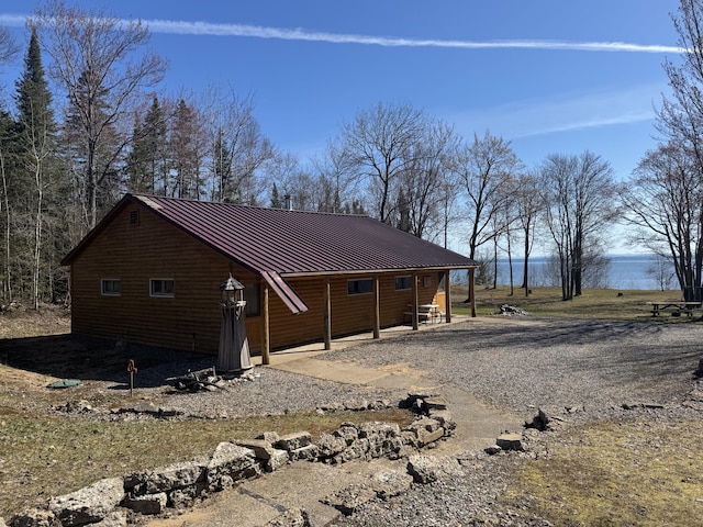 view of home's exterior featuring a water view, metal roof, driveway, and log veneer siding