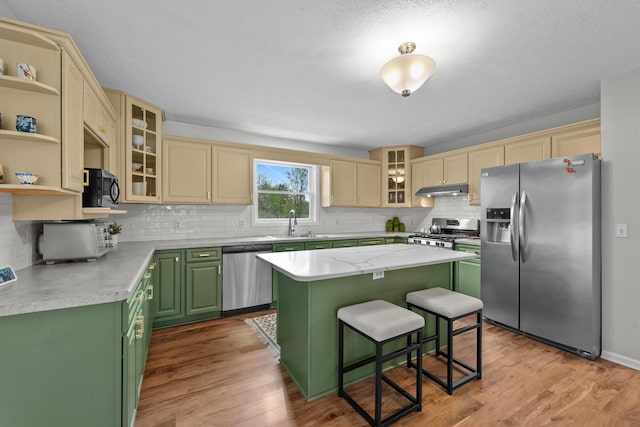 201 Country Ct, Houghton Lake, MI 48629 - kitchen featuring appliances with stainless steel finishes, green cabinetry, under cabinet range hood, a kitchen island, and wood finished floors