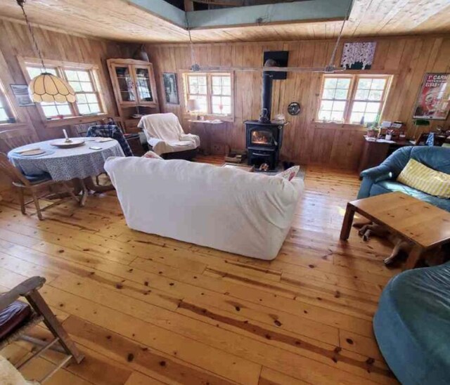 4550 E Simmons Rd, Hessel, MI 49745 - living area with a wood stove, wood walls, hardwood / wood-style floors, and wood ceiling